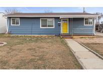 Charming single-story home featuring a blue exterior, a bright yellow front door, and a covered front porch at 4211 E 69Th Ave, Commerce City, CO 80022