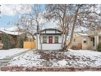 Charming white brick home with red door, landscaping, and fenced yard at 1209 Harrison St, Denver, CO 80206