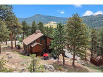 Stunning mountain home with a spacious deck, red umbrella, and lush green trees at 7282 Silverhorn Dr, Evergreen, CO 80439