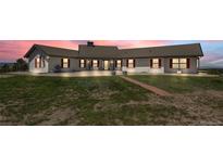 Charming single-story home with a metal roof, large windows, red shutters and well-kept lawn at sunset at 30999 Kootney St, Elizabeth, CO 80107