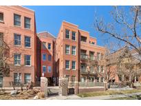 Brick building featuring multi-level balconies and courtyard with mature trees at 1631 N Emerson St # 407, Denver, CO 80218