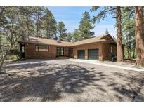 Charming single story house with gravel driveway, wood siding, and an attached two car garage at 8782 S Ault Ln, Morrison, CO 80465