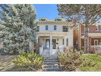 Charming white brick two-story home with a welcoming front porch and landscaped front yard at 636 N Logan St, Denver, CO 80203