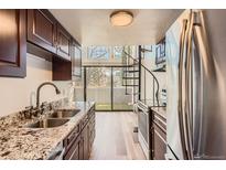 Modern kitchen with stainless steel appliances, granite countertops, dark wood cabinets, and a spiral staircase at 6470 S Dayton St # K12, Englewood, CO 80111