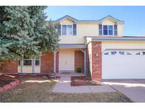 Charming two-story home with brick accents, a well-manicured lawn, and a mature tree at 8179 S Corona Way, Centennial, CO 80122