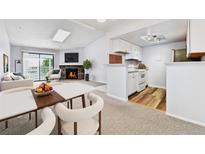 Cozy living room featuring a stone fireplace, natural light, and an adjacent modern kitchen with white cabinets at 910 S Walden St # 201, Aurora, CO 80017