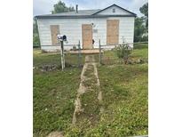 View of a boarded-up home with a weathered walkway, a mailbox, and a chain-link fence at 3701 W 9Th Ave, Denver, CO 80204