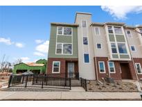 Attractive multi-story townhome featuring brick accents, muted green siding, and a black metal railing at 14283 Currant St, Broomfield, CO 80020