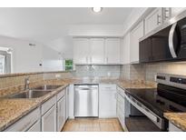 Bright kitchen features stainless steel appliances, granite countertops and gray subway tile backsplash at 11 W Ellsworth Ave # 22, Denver, CO 80223