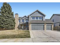 Charming two-story home with a three-car garage and brick and blue siding and large tree at 6493 W 98Th Ct, Westminster, CO 80021