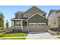 Two-story home with a covered porch, two-car garage, and well-maintained lawn and garden at 627 Nightsky St, Erie, CO 80516