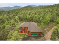 Aerial view of the brown home with a green garage door nestled in a lush forest at 29266 S Sunset Trl, Conifer, CO 80433