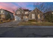 Charming two-story home with a stone facade and gray siding, set against a colorful sky at dusk at 13694 Cherry St, Thornton, CO 80602