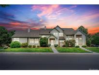 Inviting two-story home with a well-manicured lawn and a charming front porch, set against a beautiful sunset sky at 10087 E Hawaii Pl, Aurora, CO 80247