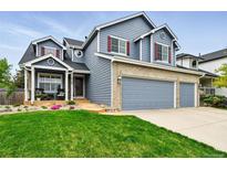 Charming two-story home with blue siding, brick accents, three-car garage and a well-manicured lawn at 14194 W Amherst Ave, Lakewood, CO 80228