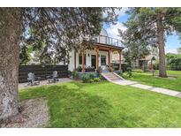 Charming two-story home featuring a well-manicured lawn and inviting front porch with wood beams at 1690 Spruce St, Denver, CO 80220