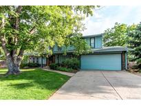 Charming two-story home featuring blue siding, mature trees, a landscaped yard, and an attached two-car garage at 11682 E Iowa Ave, Aurora, CO 80012