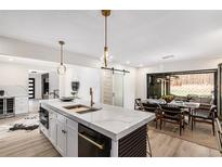 Bright, modern kitchen boasts a large island with stone countertops and gold hardware at 2140 Tabor Dr, Lakewood, CO 80215