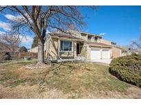 Charming two-story home with a well-maintained lawn and mature tree providing shade on a sunny day at 7345 S Eagles Nest Cir, Littleton, CO 80127