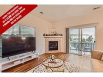 Bright living room with a fireplace and access to an outdoor patio, blending indoor and outdoor living at 14700 E 104Th Ave # 2802, Commerce City, CO 80022