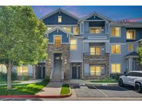 Inviting townhome featuring stone accents, a well-maintained lawn, and assigned parking spaces at 5255 Memphis St # 317, Denver, CO 80239