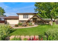 Charming home with a manicured lawn, flower beds, and a welcoming front entrance at 5870 Quail St, Arvada, CO 80004