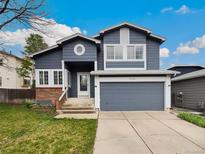 Charming two-story home features a gray exterior, attached garage, and well-maintained front yard at 8536 S Upham Way, Littleton, CO 80128