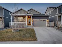 Charming home with a gray exterior, stone accents, a well-maintained lawn, and a two-car garage at 6905 Fraser Cir, Frederick, CO 80530