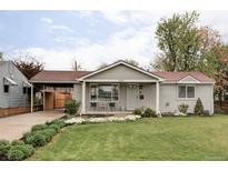 Charming home with a well-manicured front yard and covered front porch with seating area at 1561 W Beekman Pl, Denver, CO 80221