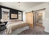 This is a main bedroom with dark accent wall and barn door to en suite bathroom at 15274 W 64Th Ln # 206, Arvada, CO 80007