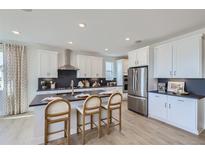Bright kitchen featuring stainless steel appliances, a dark counter island with seating and light wood floors at 4110 Grand Lake St, Brighton, CO 80601
