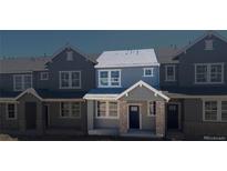 Charming townhome featuring a covered entryway with brick columns, large windows, and blue siding at 17117 W 91St Ln, Arvada, CO 80007