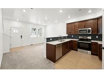 Modern kitchen features stainless appliances, wooden cabinets, and beautiful tile backsplash at 17117 W 91St Ln, Arvada, CO 80007