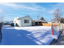 Ranch home with snowy front yard and fenced area at 6661 Clermont St, Commerce City, CO 80022