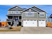 Charming gray two-story home with stone accents and a three-car garage at 5895 E Conservation Dr, Frederick, CO 80504