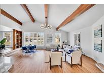 Bright living room with vaulted ceilings, exposed beams, hardwood floors, and large windows allowing natural light to flood the room at 6220 E 5Th Ave, Denver, CO 80220