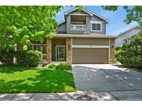 Charming two-story home with stone accents, a well-manicured lawn and a two car garage at 5755 W Berry Ave, Denver, CO 80123