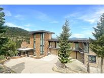 Stunning stone home boasts a modern design with expansive windows and a spacious driveway at 180 Outpost Ln, Evergreen, CO 80439