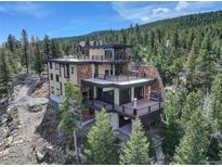 Stunning multi-level home boasting stone accents and expansive decks with mountain views nestled among lush trees at 180 Outpost Ln, Evergreen, CO 80439