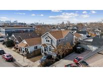 Charming gray two-story home with inviting curb appeal and a view of the city skyline in the background at 4445 Pearl St, Denver, CO 80216