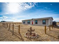 Charming single-Gathering home featuring a bright red front door and a rustic cactus decoration in the yard at 6201 S Vanderhoof St, Bennett, CO 80102