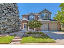 Charming two-story home boasts mature landscaping, a brick facade, and attached two-car garage at 9261 Millcreek Ct, Highlands Ranch, CO 80126