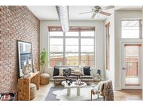 Bright living room with exposed brick wall, large windows, and comfortable seating at 7700 E 29Th Ave # 411, Denver, CO 80238