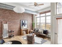 Spacious living area featuring an exposed brick wall, hardwood floors, and modern furniture at 7700 E 29Th Ave # 411, Denver, CO 80238