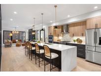 Open-concept kitchen with quartz island, pendant lighting, hardwood floors, and stainless steel appliances at 3047 S Cherokee St, Englewood, CO 80110