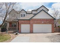 Charming two-story home with a brick facade and a spacious two-car garage, set against a bright blue sky with scattered clouds at 10572 Jaguar Gln, Lone Tree, CO 80124