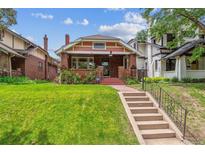 Charming brick home features a well-manicured lawn, landscaped front yard, and inviting front porch at 869 S Williams St, Denver, CO 80209