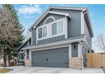 Side view of gray two-story home with a two-car garage and manicured landscape at 9208 W 100Th Pl, Broomfield, CO 80021