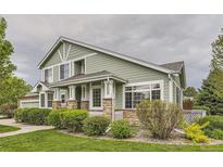 Inviting green home exterior featuring stone accents, manicured lawn, and beautiful landscaping at 7498 W Saratoga Pl, Littleton, CO 80123