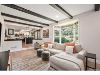 Bright living room with a comfortable couch and dark wood beam ceiling overlooks the kitchen at 6251 W 74Th Ave, Arvada, CO 80003